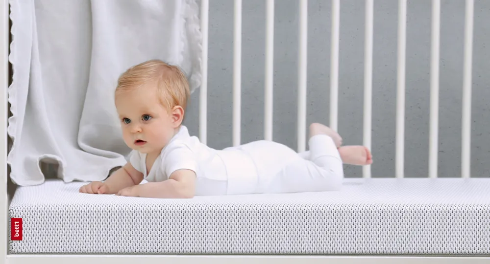 Baby liegt auf einer Kindermatratze