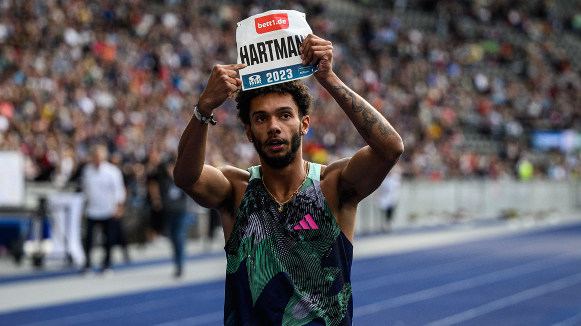Foto: Ein Läufer auf einer Tartanbahn hält mit beiden Armen ein Schild mit Namen und bett1-Logo über seinen Kopf.