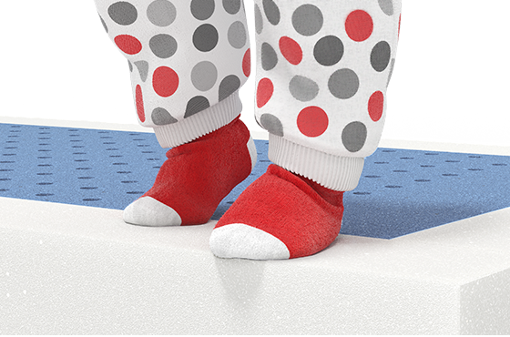Imagen de un colchón con un par de calcetines rojos y blancos con puntos grises sobre la superficie, destacando el confort para bebés.