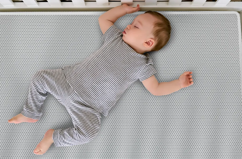 Ein Baby liegt auf dem Rücken in einem Babybett.