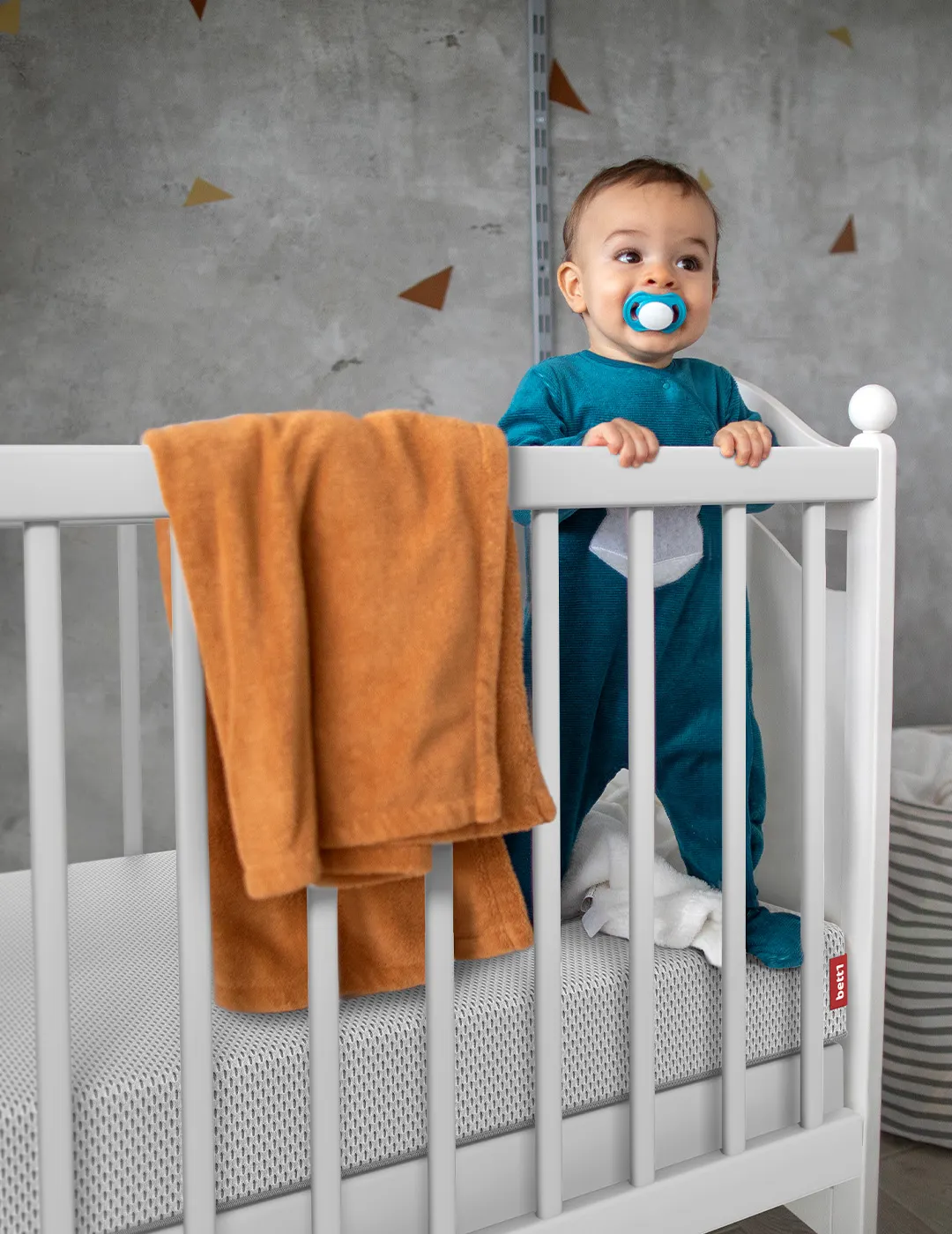 Baby steht in Gitterbett auf der SuperBreeze Kindermatratze