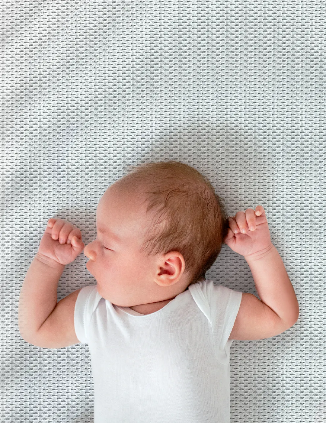Ein Baby liegt rücklings auf der SuperBreeze Kindermatratze.