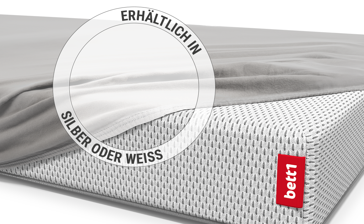 Die BODYGUARD® Kindermatratze ist bis auf eine Ecke mit dem Kinder-Spannbettlaken in Silber bezogen. Zoom auf das Laken in der weißen Farbvariante. Text: Erhältlich in Silber oder Weiß