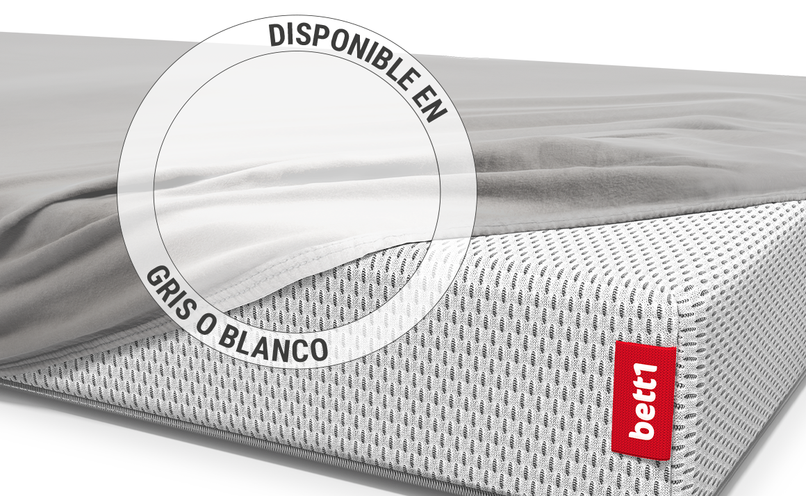 El colchón infantil BODYGUARD® está cubierto hasta una esquina con una sábana ajustable para niños en color plateado. Zoom en la sábana en la variante de color blanco. Texto: Disponible en plata o blanco.