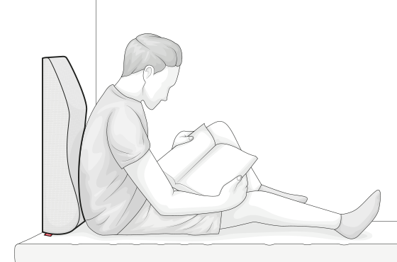  Ilustración de una persona sentada contra una almohada inclinada, utilizando la almohada para leer cómodamente con apoyo en la espalda.