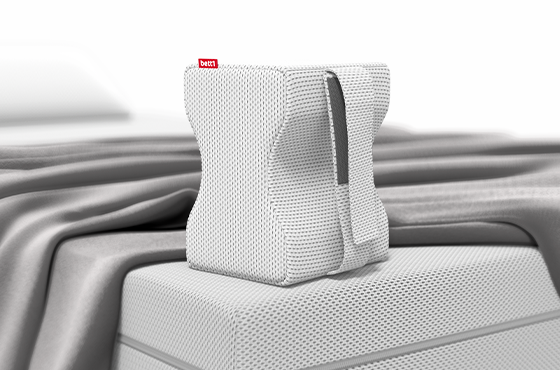 Imagen de la almohada para las rodillas BODYGUARD® de bett1.es colocada sobre una cama, mostrando su forma ergonómica diseñada para mejorar la postura al dormir.