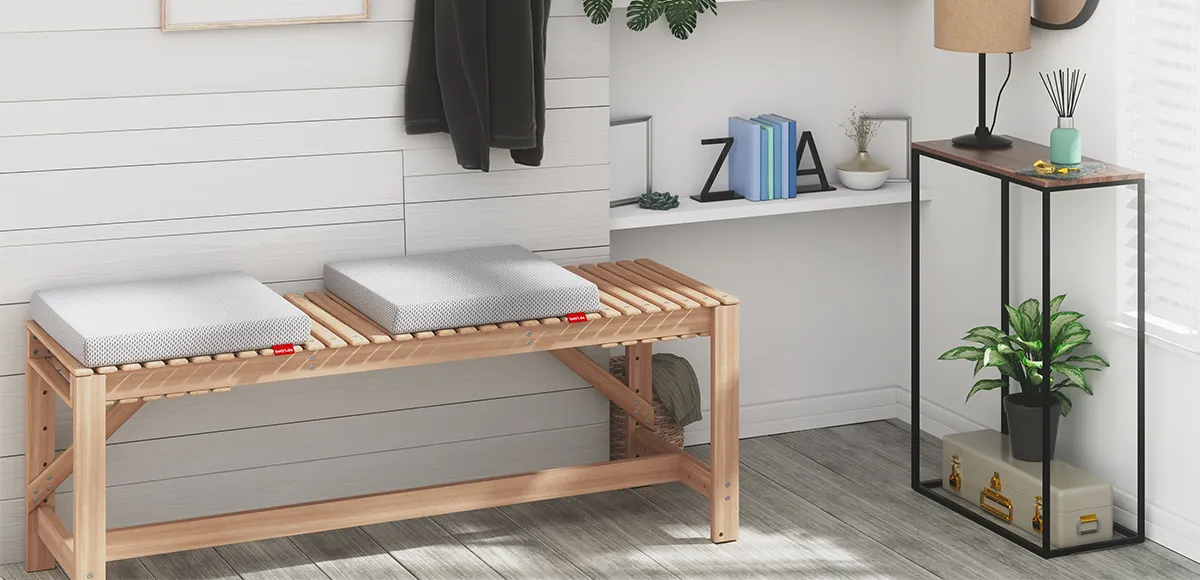 Cojín para silla Bodyguard en un entorno interior, sobre una silla de madera junto a una mesa baja y una planta decorativa.