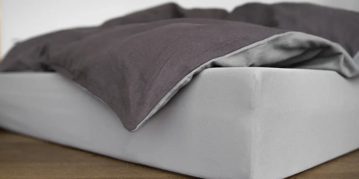 Un colchón en el suelo con ropa de cama bicolor encima