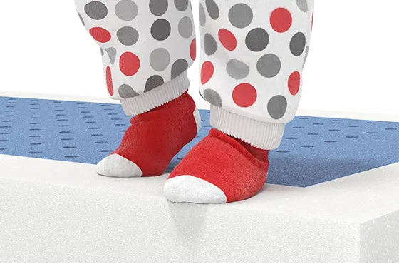 Imagen de un colchón con un par de calcetines rojos y blancos con puntos grises sobre la superficie, destacando el confort para bebés.