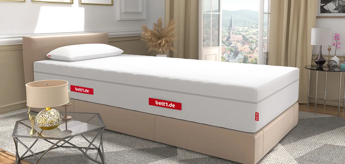 Colchón BODYGUARD® sobre una base tapizada beige en un dormitorio elegante con vistas a la ciudad.