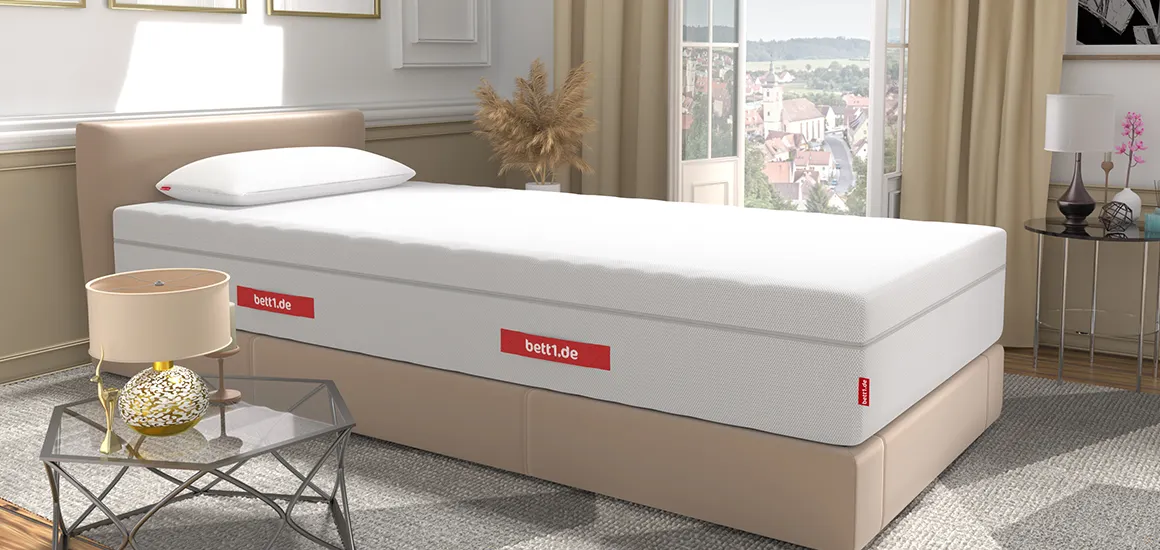 Colchón BODYGUARD® sobre una base tapizada beige en un dormitorio elegante con vistas a la ciudad.