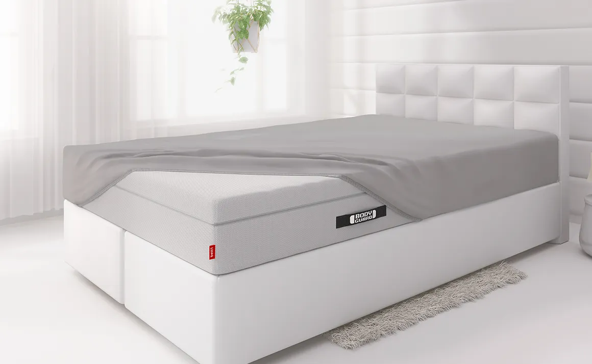 Imagen de una sábana bajera ajustada en una cama con colchón BODYGUARD®, mostrando un ajuste perfecto y suave en un entorno moderno.