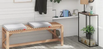 Cojín para silla Bodyguard en un entorno interior, sobre una silla de madera junto a una mesa baja y una planta decorativa.