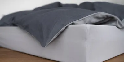 Un colchón en el suelo con ropa de cama bicolor encima