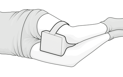 Illustration: Eine Person in Seitenlage hat das Kniekissen zwischen die Oberschenkel geklemmt.	