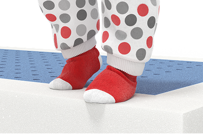 Imagen de un colchón con un par de calcetines rojos y blancos con puntos grises sobre la superficie, destacando el confort para bebés.